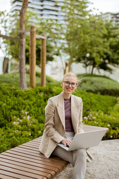 Young woman works on laptop in garden area during bright day