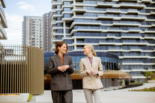 Women walk and talk in front of modern buildings on a sunny day in the city