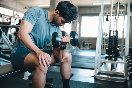 Man dumbbell gym exercise fitness bench muscle workout man lifting dumbbell on bench inside modern gym with focused expression and athletic training routine