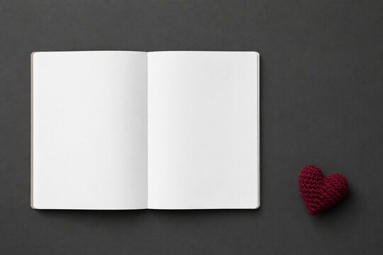 Blank open journal notebook spread mockup on dark slate with burgundy crochet heart