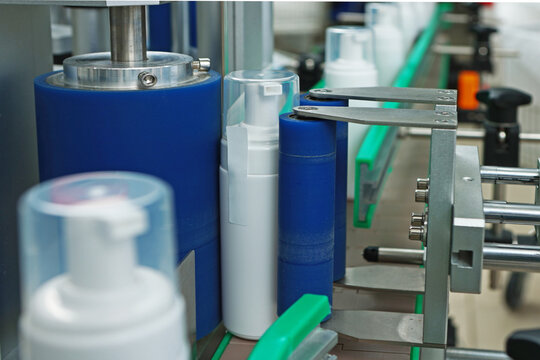 Bottles without labels on conveyor of cosmetics factory. Manufacture of cosmetics and skin care products. White plastic bottle