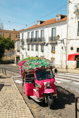 Pink tuk tuk parked on a steep cobblestone street in lisbon, portugal, on a sunny day © Alberto