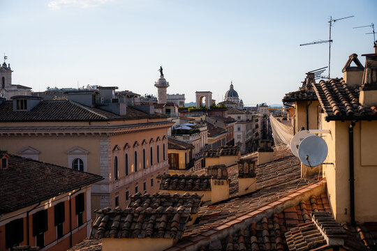 Panoramic cityscape of Rome rooftop view with Trajan Column and domes at sunset