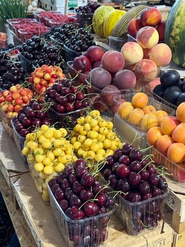 Fresh cherries peaches and apricots at a colorful farmers market display