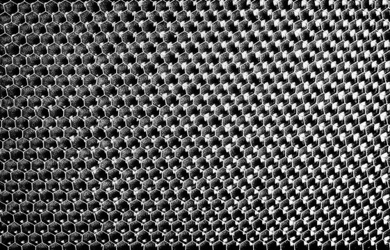 Monochrome macro shot of a shallow aluminum hexagonal grid against a shiny black backdrop