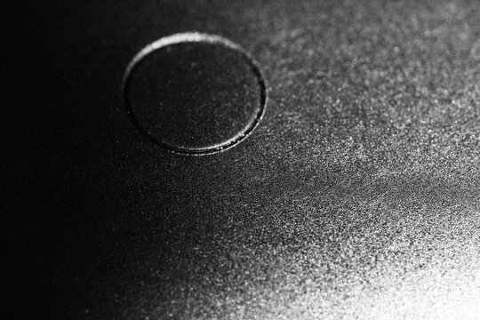 Monochrome macro shot of the curved surface of a plastic object with a subtle round button