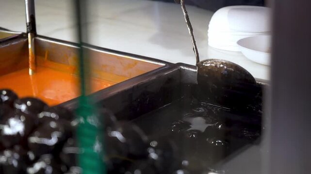 Dark sauce appetizer served with ladle at food market counter