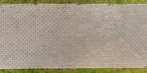 Fototapeta premium top view of surface of pedestrian path with paving slabs with the border of light and shadow