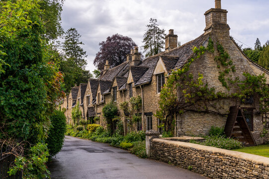 Historic village street scene in Castle Combe, Wiltshire, England. Traditional stone homes line a curved road.