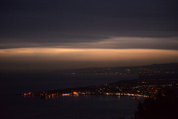 Fototapeta premium Sunset-to-night seascape from Taormina with glowing coastal lights