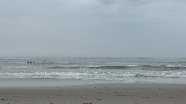 Two jet skis quickly zipping by a group of nonrecognizable bathers in the ocean.