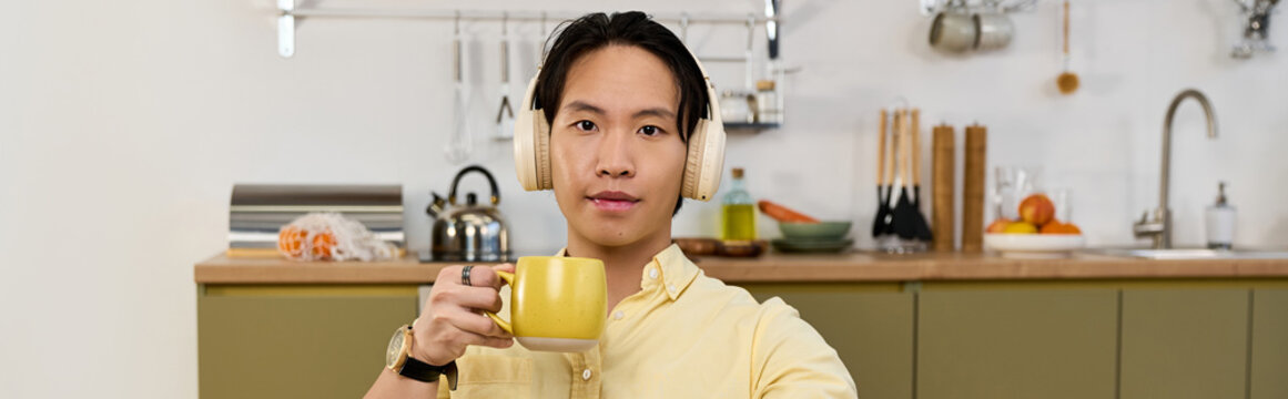 Young asian man enjoys coffee in his modern apartment while relaxing at home