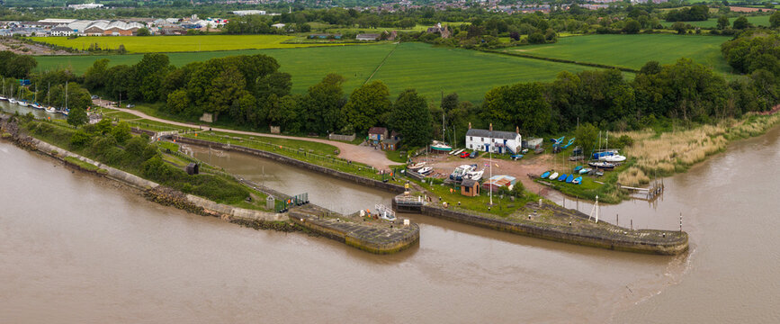 Aerial drone view of Lydney Harbour and the River Severn with surrounding landscape in Gloucestershire, England under cloudy skies.