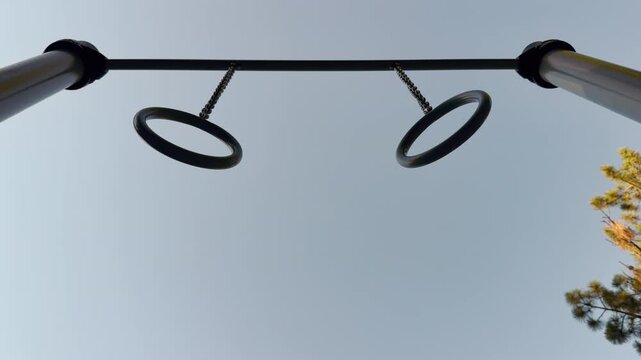 athletic rings hang motionless from chains under an open sky. The calm, minimal view inspires a peaceful feeling of focus and physical freedom.