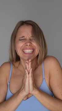 Young blonde woman claps her hands and joyfully shouts bravo, expressing admiration, excitement, celebration and emotional support in a cheerful communication and success concept on a grey background