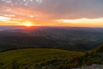 Fototapeta premium Scenic panoramic view of green mountain ridges and a hiking trail under a clear sunset sky. Peaceful Carpathian landscape, journey and travel background with copy space, low key, selective focus
