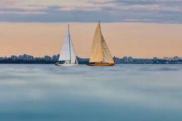 Fototapeta premium A lot of sailing boats are in sailing regatta in the Gulf of Finland at sunset, Russia, St.Petersburg, hot race of several yachts, teamwork, yachtsman