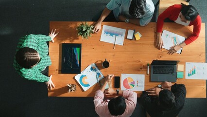 Obraz premium Top down view of manager holds tablet display increasing sales and placed on meeting table. Group of diverse business team clapping hands to celebrate successful product at meeting room Convocation.