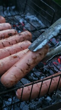 Vertical video. Summer barbecue, cookout. Grilling sausages during summer picnic
