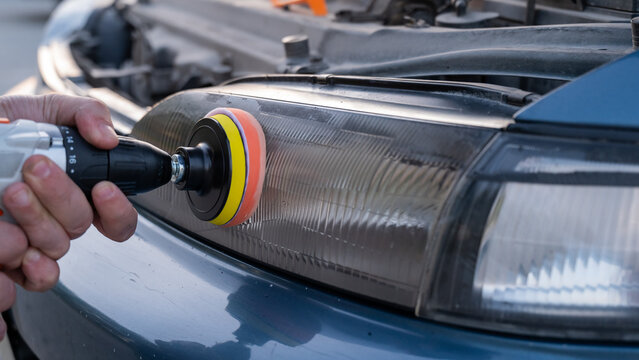 The process of polishing car headlights outdoors. 