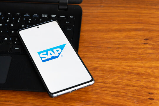 Punta Arenas, Chile &ndash; July 2, 2026: The SAP logo displayed on a smartphone screen resting on a laptop keyboard over a wooden table background