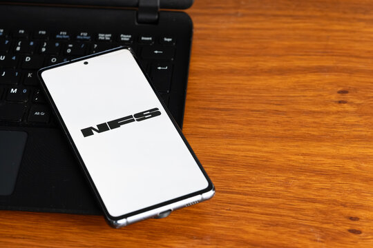 Punta Arenas, Chile &ndash; July 3, 2026: The Need for Speed (NFS) video game logo displayed on a smartphone screen resting on a laptop keyboard over a wooden table background