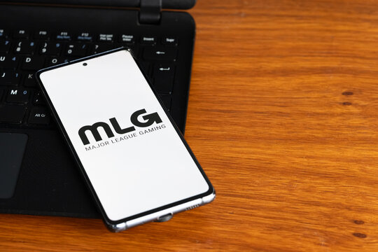 Punta Arenas, Chile &ndash; July 3, 2026: The Major League Gaming (MLG) logo displayed on a smartphone screen resting on a laptop keyboard over a wooden table background