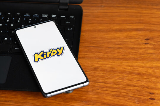 Punta Arenas, Chile &ndash; July 6, 2026: The Nintendo Kirby video game franchise logo displayed on a smartphone screen resting on a laptop keyboard over a wooden table background
