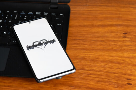 Punta Arenas, Chile &ndash; July 6, 2026: The Kingdom Hearts video game franchise logo displayed on a smartphone screen resting on a laptop keyboard over a wooden table background