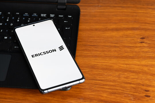 Punta Arenas, Chile &ndash; July 8, 2026: The Ericsson telecommunications company logo displayed on a smartphone screen resting on a laptop keyboard over a wooden table background