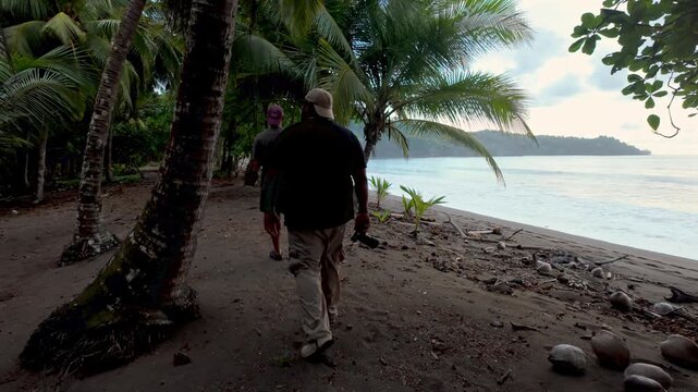 Two male explorers walking on tropical beach path