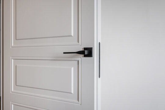door handle on white wooden door in interior. Knob close-up elements. Door handle, fittings for interior design