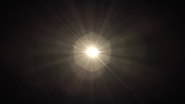 A bright sun with radiating rays shining through a mostly dark sky, creating a glowing effect with flare and lens effects during daytime, highlighting natural sunlight.