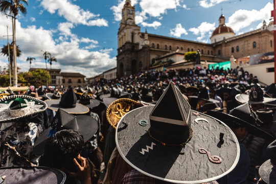 Indigenous dancers wearing traditional big black hats celebrating Inti Raymi festival in the main square of Cotacachi, Ecuador