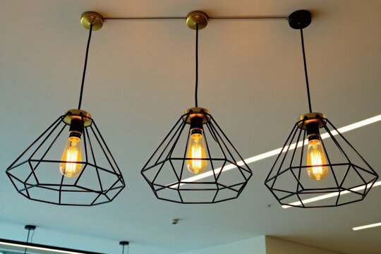 Three retro diamond wire frame pendant lights hang from ceiling. Edison bulbs emit warm yellow glow. Modern industrial interior design element adds stylish illumination.
