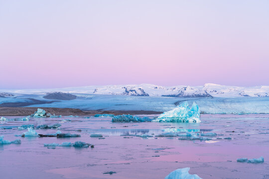 Blue icebergs floating in Jokulsarlon glacial lagoon at pastel sunset