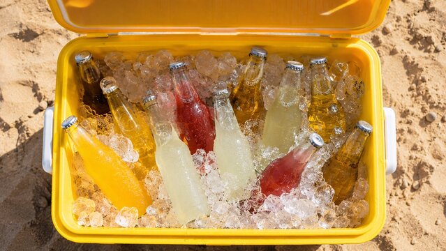 Close-up of refreshing colorful soda bottles chilling in a cooler box filled with crushed ice on a hot summer day