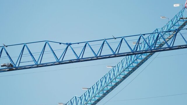 Construction crane jib moving against blue sky