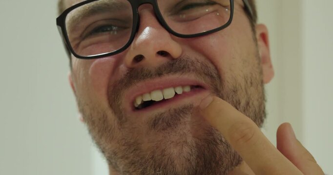 Close-up of a man trying to remove food stuck between his teeth using his finger. Concept of oral hygiene, dental discomfort, and everyday personal care.
