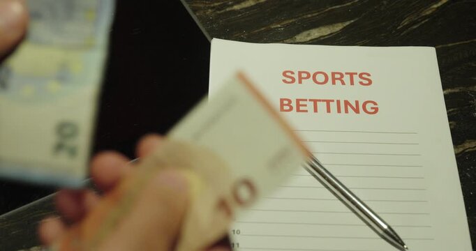 Close-up of a person counting cash beside sports betting notes. Concept of gambling, betting winnings, financial risk, and sports wagering.