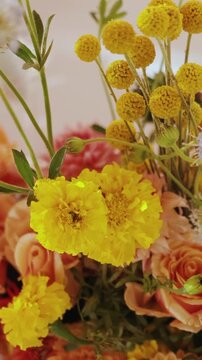 Vertical video. Wedding floral arrangement with wildflowers, orange roses and candles on restaurant table.