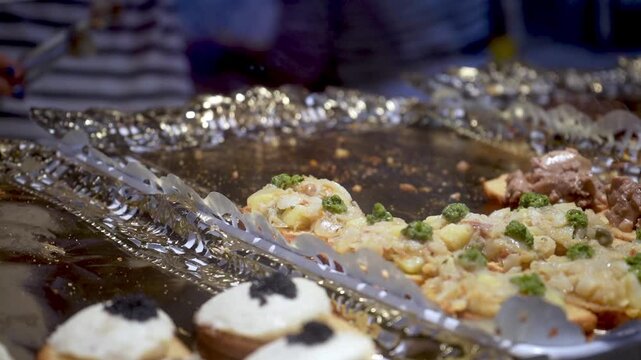 Staff hand placing tapas with tongs during premium catering service