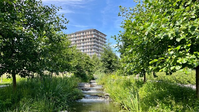 Urban park stream flowing past modern building in OSLO