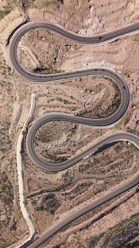 Drone vertical video of winding switchback road through arid mountain landscape near Potrerillos, Argentina