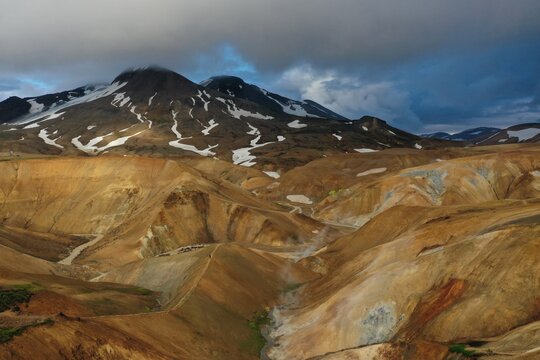 Aerial view of the geothermal landscape of Kerlingarfjoll with colorful rhyolite hills, steam vents, and snow patches in Blonduos, Hunabyggd, Iceland.