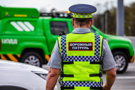 A traffic police officer on a summer city street next to a police car