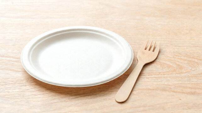 Eco friendly disposable paper plate with wooden fork on wood table, empty plate, wooden cutlery, picnic tableware, sustainable catering, compostable plate, biodegradable dish, food concept.