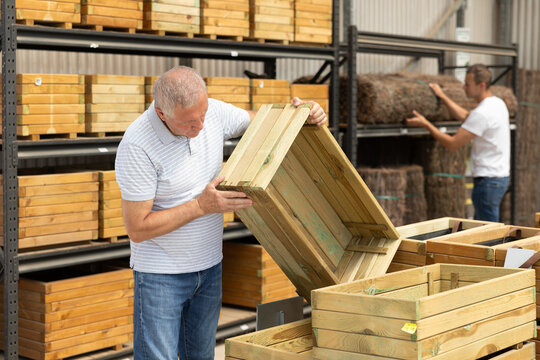 Elderly man ooking for functional wooden box for growing flowers