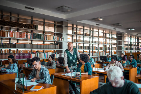 Teacher assisting university students studying in library