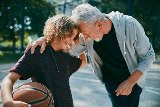 Grandfather and grandson playing basketball on outdoor park court
